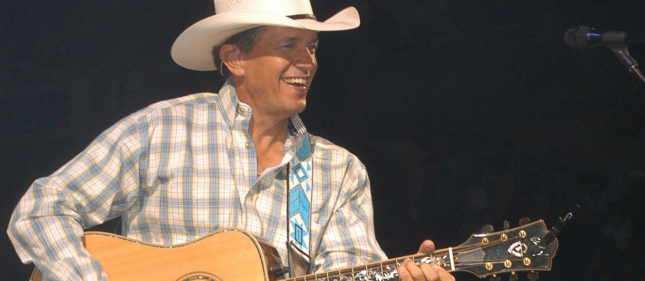 George Strait playing a guitar on stage.